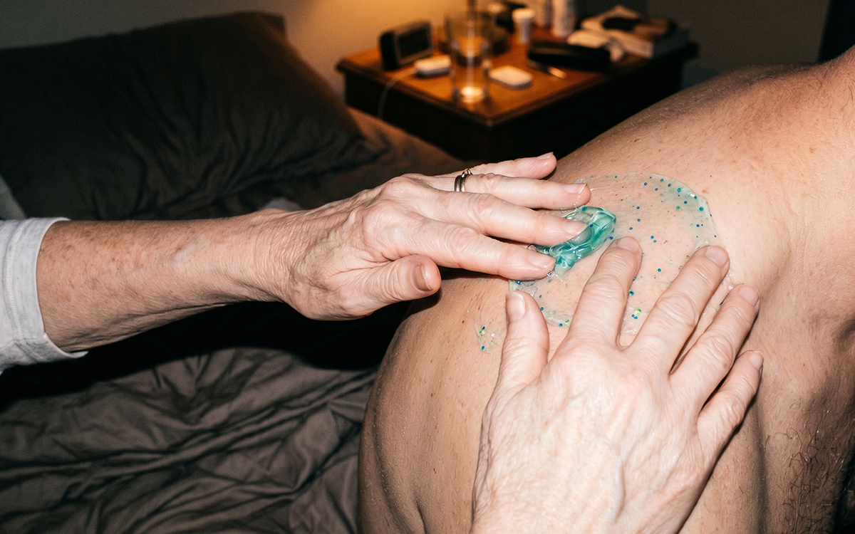 Man applying Kinzeno gel to his shoulder with a look of relief